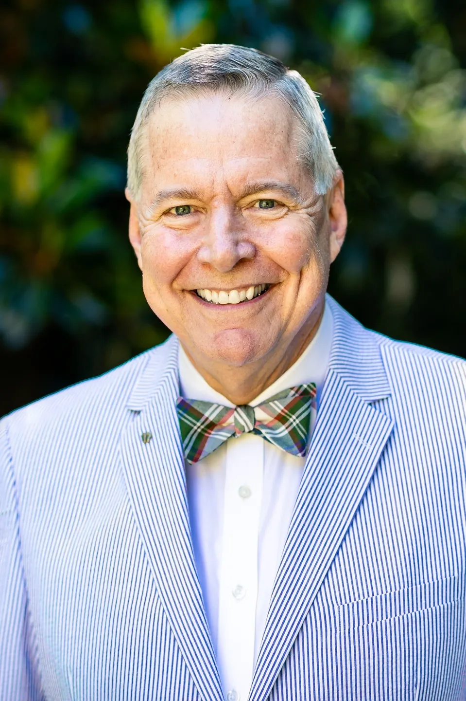 A man in a suit and bow tie smiling for the camera.